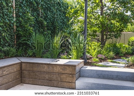 Cozy shady seating area made of concrete and wood in a garden Royalty-Free Stock Photo #2311033761
