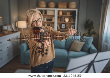 Mature senior caucasian woman learn to play violin practice at home Royalty-Free Stock Photo #2311046159