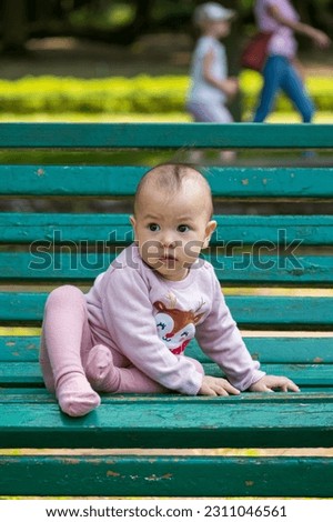A baby girl playing in the park, sitting on the bench at park
