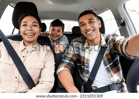 Excited multiracial family driving auto, boy pointing finger showing destination of road trip, traveling on vacation by car and enjoying ride Royalty-Free Stock Photo #2311051309