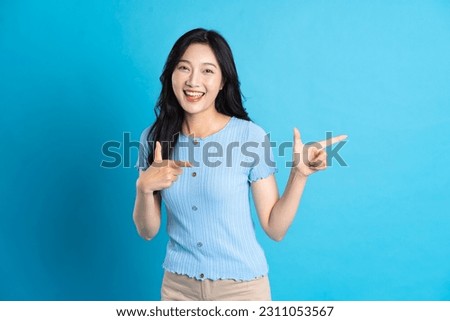 Portrait of a happy smiling asian girl posing on a blue background Royalty-Free Stock Photo #2311053567