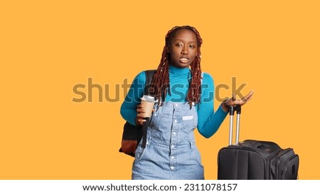 Young female tourist drinking cup of coffee in studio, preparing to leave on vacation with baggage and trolley bags. Excited woman enjoying beverage before travelling to holiday journey.