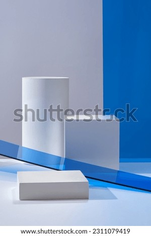 Minimal art background with empty space for cosmetics, business branding and product presentation. Against a light background, cylinder white podium decorated with blue acrylics sheets.