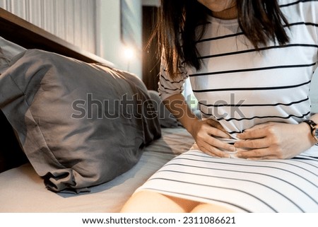 Asian middle aged woman touch abdomen,severe stomach pain,Premenstrual Syndrome,sick female having period cramps,abdominal pain during menstrual period,Menstruation,Dysmenorrhea and Gynecology concept Royalty-Free Stock Photo #2311086621