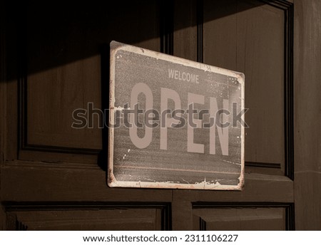 Sign with message Welcome OPEN on black wooden door
