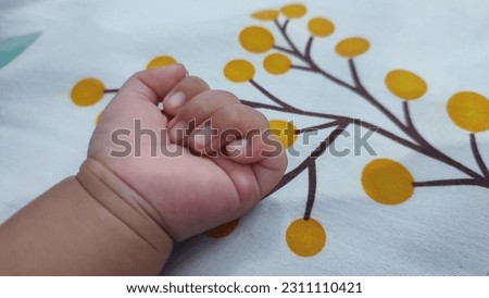 left hand of baby lays on bed