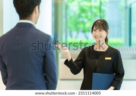 female asian receptionist serving customer in a hotel lobby Royalty-Free Stock Photo #2311114005