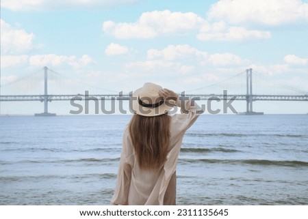 Woman traveller is sightseeing and looking at Gwangalli Beach in Busan, South Korea.  Royalty-Free Stock Photo #2311135645