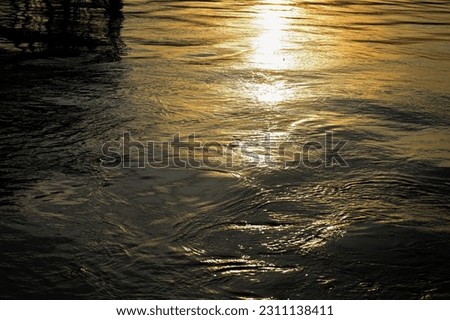 The image of sunlight hitting the water surface of the Bang Pakong River creates a golden glow on the water that hits the waves of the water.