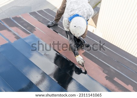 A male craftsman painting a tin roof Royalty-Free Stock Photo #2311141065