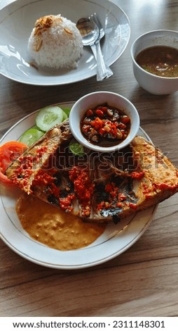 Picture grilled fish rich with spices and covered with chili sauce on the meat, perfect texture of caramel and chips, complemented by white rice and extra soy sauce