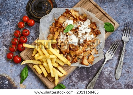  Portion of Spicy  kebab  Chicken  duner  gyros with french fries and garlic sauce  on  wooden board Royalty-Free Stock Photo #2311168485