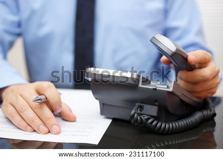 Businessman is picking up the headset for help, while reading legal document