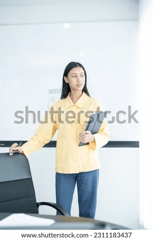 Confident businesswoman holding tablet and smiling at the camera, in meeting room on white background.