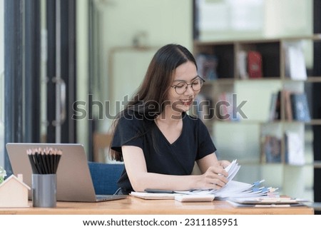 Asian businesswoman working in piles of paper files to find and review unfinished documents in the financial document folder business agreement on the desk in the office.
