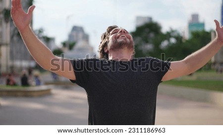 Elated young man gazing up at sky feeling the Grace of God. Believer feeling grateful and FAITH raises arms to sky feeling GRATITUDE Royalty-Free Stock Photo #2311186963