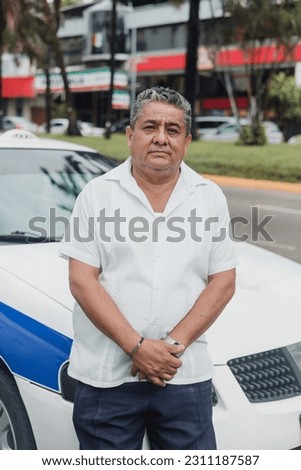 portrait of latin taxi driver senior man with car on background at city street in Mexico in Latin America, Hispanic adult people Royalty-Free Stock Photo #2311187587