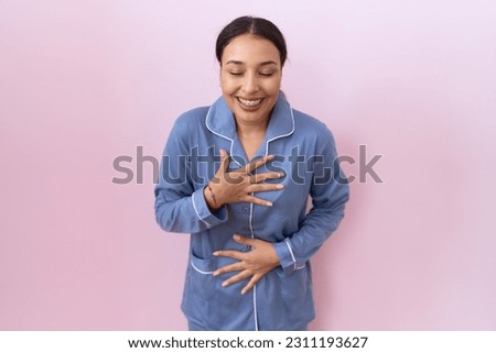 Young arab woman wearing blue pajama smiling and laughing hard out loud because funny crazy joke with hands on body. 