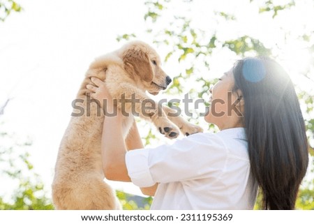 Asian women playing Golden Retriever puppy in the garden. 