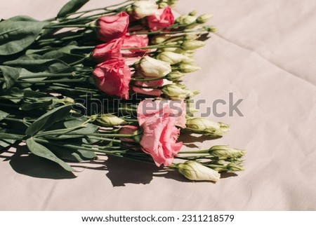 Gently pink eustomas on the beige background. Natural background with a bouquet of flowers with copy space. Flat lay