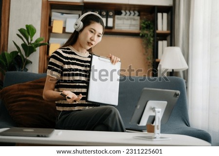Asian woman using the smartphone and tablet on the sofa at home