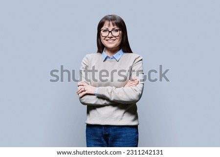 Positive middle aged woman posing over grey studio background