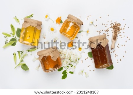 Jars with different types of honey on color background, top view