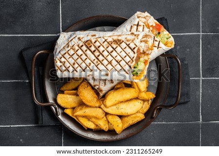 Shawarma Shaurma kebab with meat, vegetable salad and french fries. Black background. Top view.