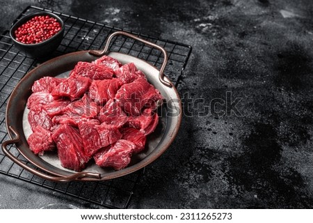Raw Diced venison dear meat for a goulash, game meat. Black background. Top view. Copy space. Royalty-Free Stock Photo #2311265273