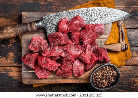 Sliced Raw venison dear meat for a stew, game meat on butcher cutting board. Wooden background. Top view. Royalty-Free Stock Photo #2311265825