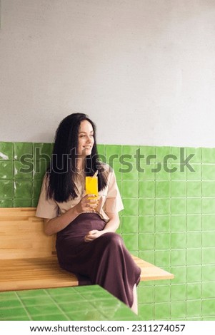 Vertical photo of young woman wear beige shirt fresh orange slice glass cocktail fresh summer on green tile background
