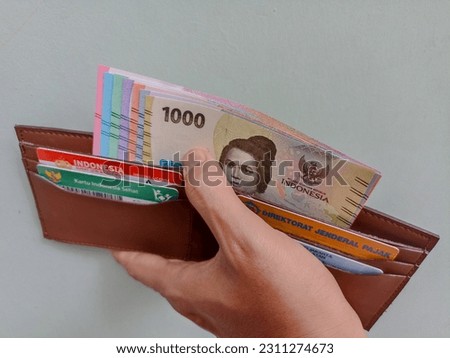 The latest collection of Indonesian rupiah banknotes that are put in a wallet that also contains driver's license, health and tax cards.