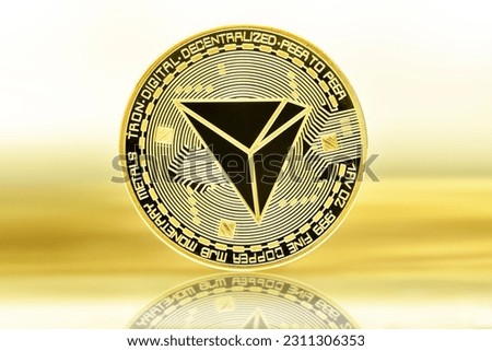 A closeup shot of TRON cryptocurrency coins on a golden background