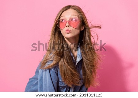Photo portrait of lovely young teenager lady pouted lips look empty space wear trendy jeans garment isolated on pink color background