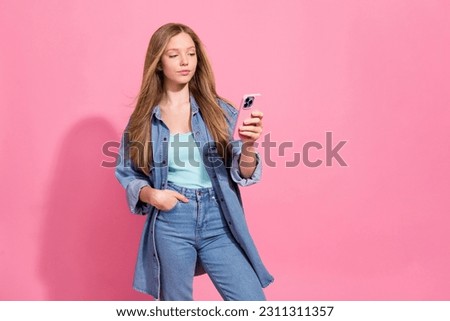 Portrait of adorable gorgeous girl addicted user wear stylish denim clothes use iphone stand empty space isolated on pink color background