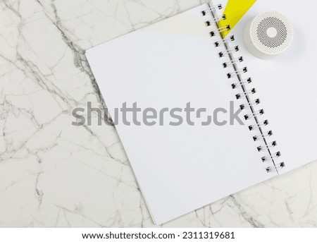 Notebook with mini speaker on marble background