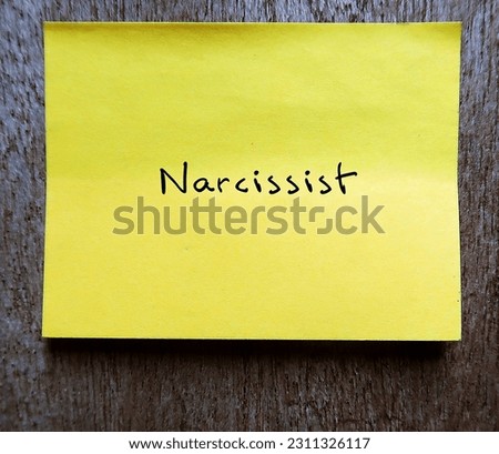 Yellow note stick on wall with handwriteen text NARCISSIST, self-centered inflated people of importance, need attention and admiration but lack empathy to others Royalty-Free Stock Photo #2311326117