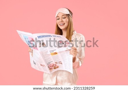 Young woman in pajamas reading morning newspaper on pink background
