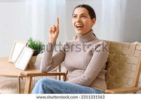 Young woman having idea in armchair at home Royalty-Free Stock Photo #2311331563