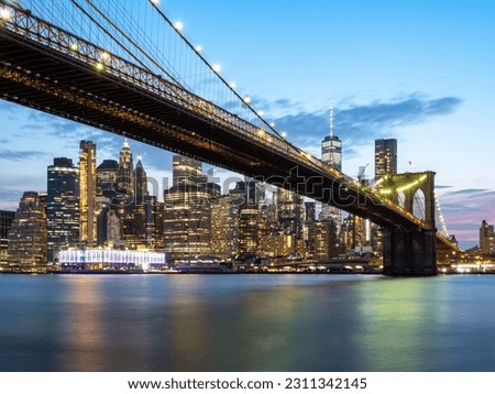 The illuminated Brooklyn Bridge with New York City skyline in he background in the United States