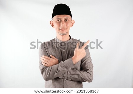 Portrait of Moslem Asian Man pointing hands and finger to the side. (explain something).
