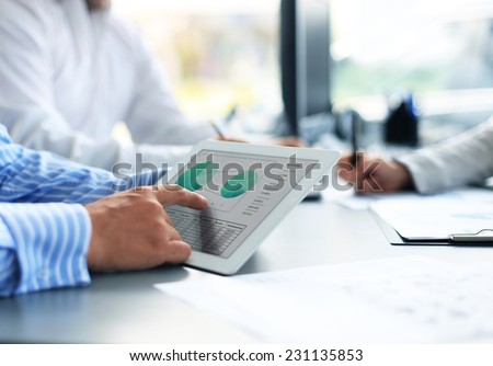 Image of human hand pointing at touchscreen in working environment at meeting 