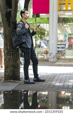 Asian man using a smart phone in the town.