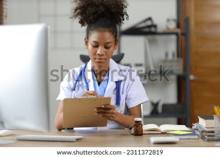 Female doctor working in the doctor's office at the hospital. Doctor working with computer and writing prescription.
