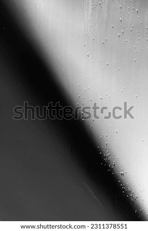 Close-up of a yacht bottom, in black and white. Keel of a white yacht with shadows and water drops on the hull.