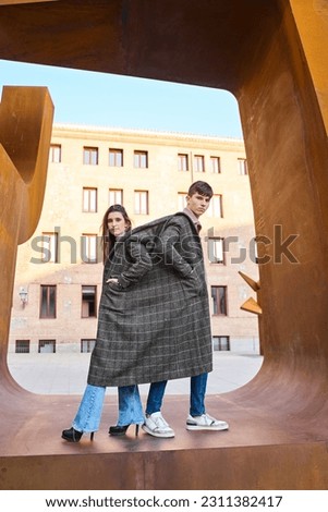 young couple sharing a coat in an artist's picture