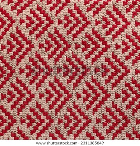 Crochet mosaic pattern. Knitted fabric with red beige geometric pattern. Crochet background.