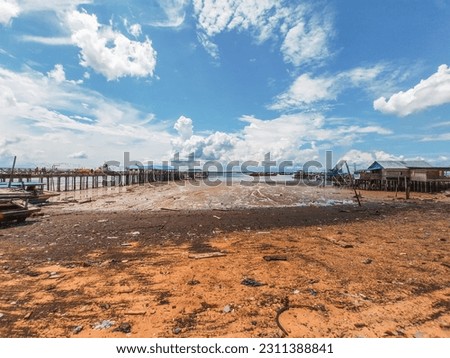 fisherman village, dumai, Riau, Indonesia. the view of the receding sea water on the beach along with the traditional stilt houses against the clear blue sky