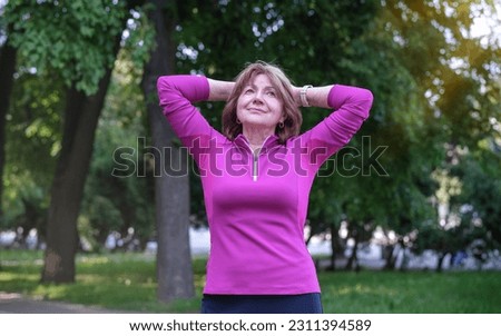 Portrait of beautiful senior woman looking at camera and smiling while standing in forest Royalty-Free Stock Photo #2311394589