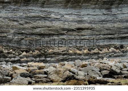 Rhythmic stratification of sedimentary rocks deposited in horizontal layers. Broken Coast of Liencres, Cantabria, Spain.  Royalty-Free Stock Photo #2311395935